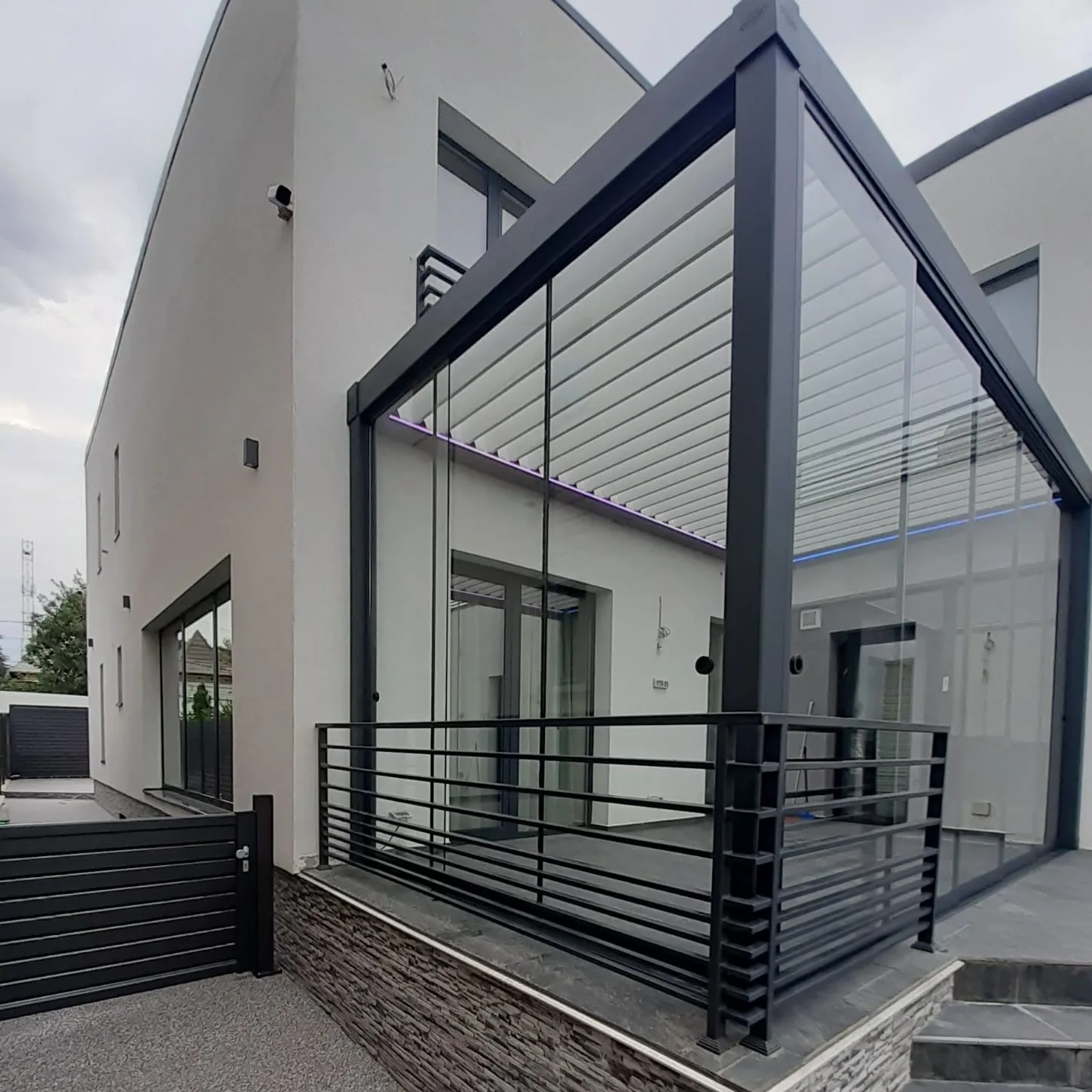 Pergola închisă cu panouri laterale din sticlă, pentru protecție completă și vizibilitate maximă