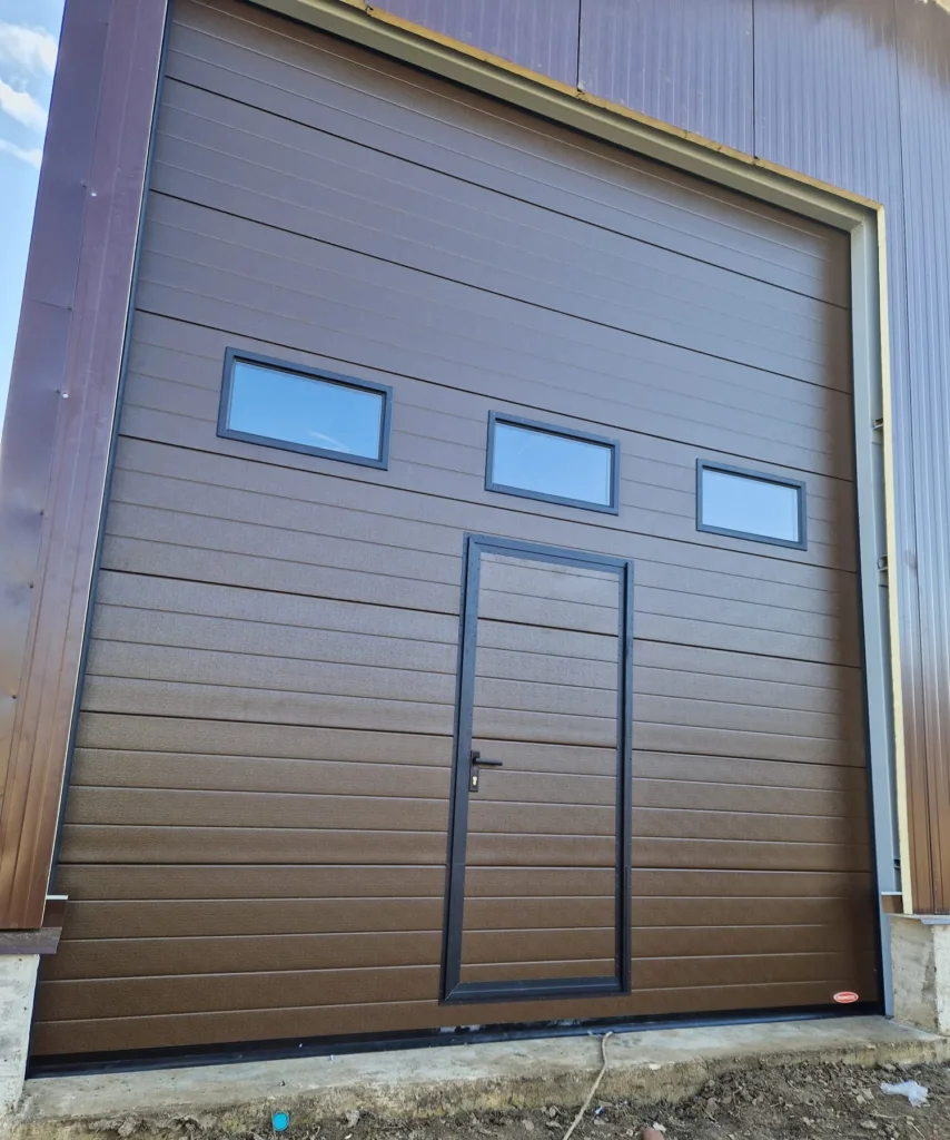 Ușă industrială cu ușă pietonală și geamuri.