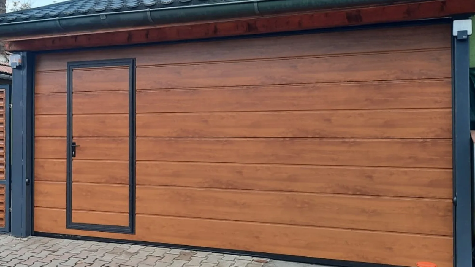 Ușă de garaj cu panouri imitație de lemn, stejar auriu, cu ușă pietonală.