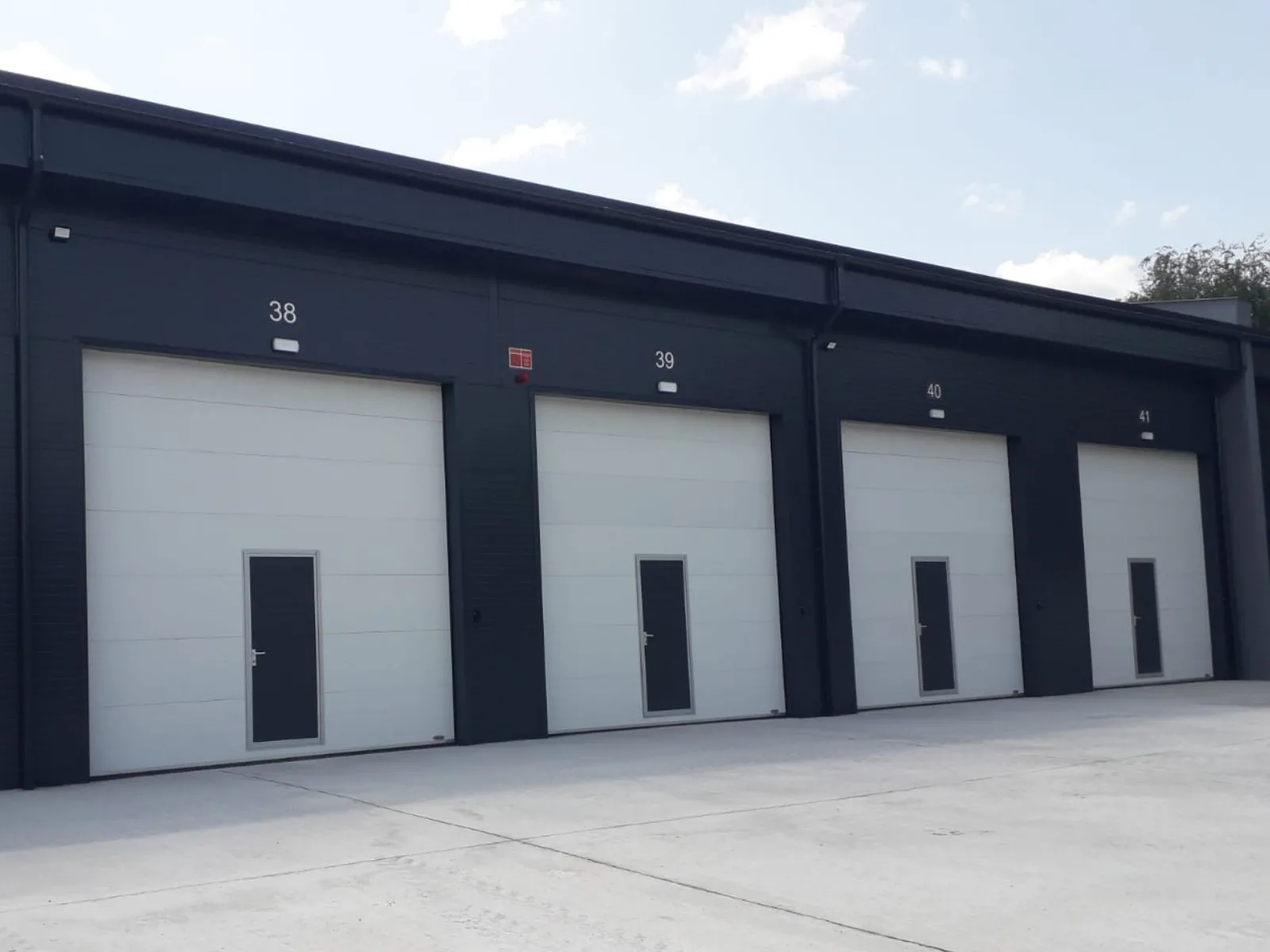 Uși industriale cu panouri alb cu uși pietonale antracit.