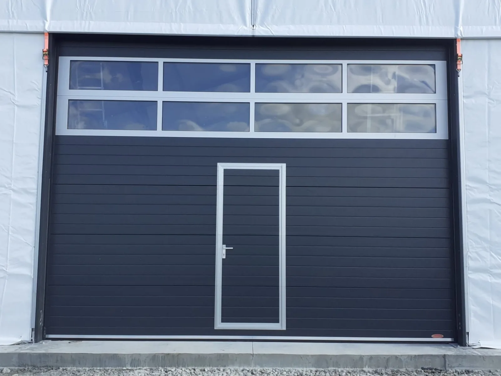Ușă industrială cu panouri antracit și vitrat.